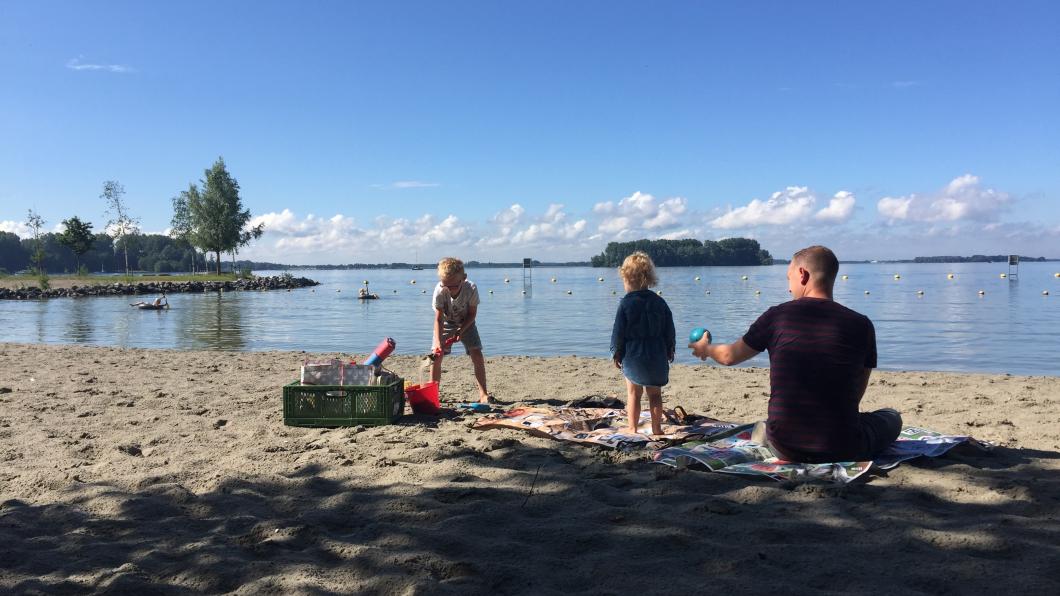 Vader met spelende kinderen op het strand in Biddinghuizen