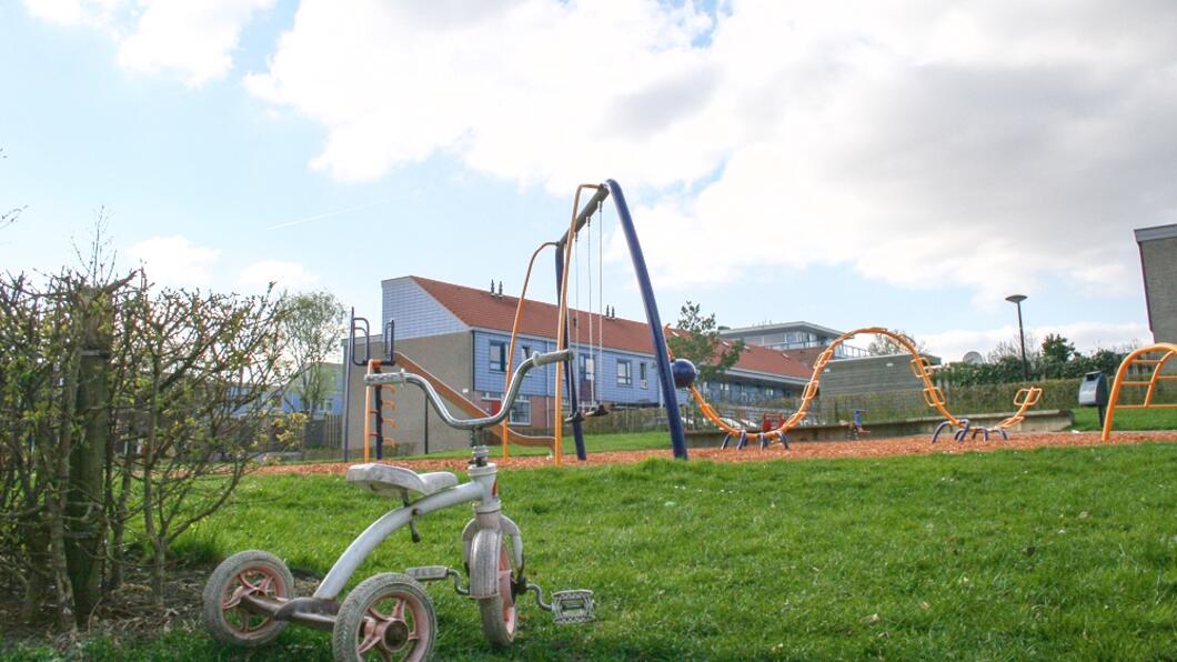 Driewielertje bij speeltuin aan een grasveld